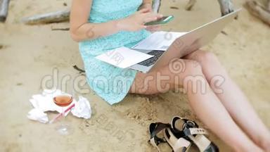 一个忙碌的年轻女子正在用一台手提电脑，手里<strong>拿</strong>着商业文件，<strong>拿起</strong>一个电话，坐着打电话